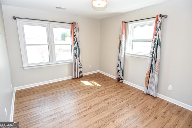 empty room featuring visible vents, light wood-style flooring, and baseboards