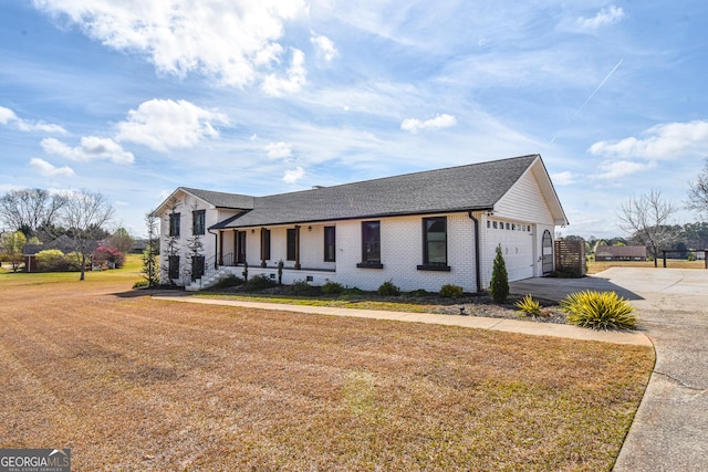 view of front of house with an attached garage, a shingled roof, concrete driveway, a front lawn, and brick siding