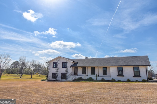 split level home with roof with shingles and a front lawn