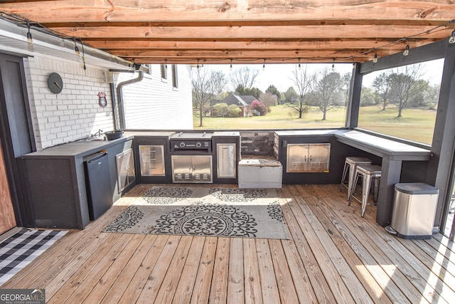 wooden terrace featuring a sink, outdoor wet bar, area for grilling, and exterior kitchen