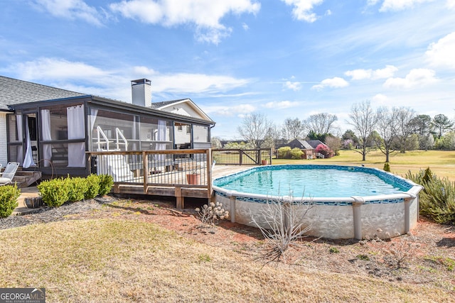 pool with a lawn, a deck, and a sunroom