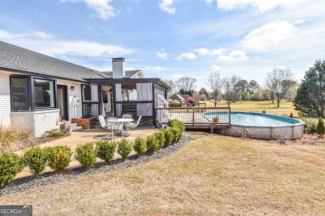 view of yard featuring an outdoor pool, a sunroom, and a patio area