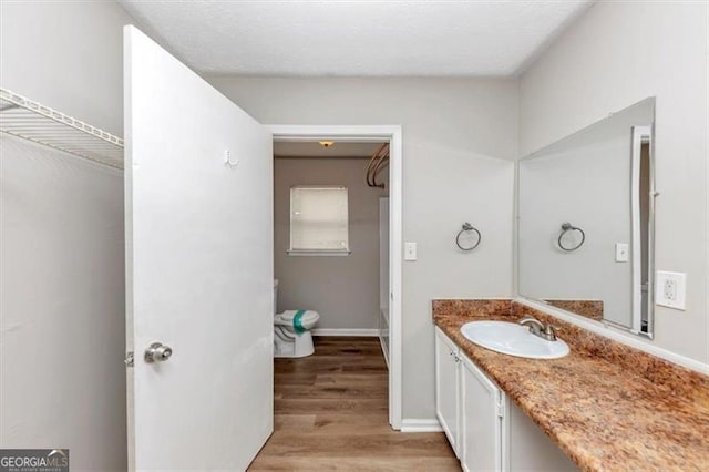 full bathroom with toilet, vanity, baseboards, and wood finished floors