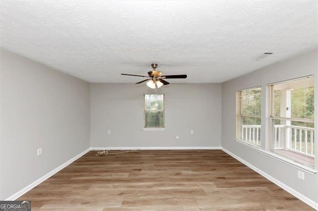 empty room with ceiling fan, light wood-style floors, baseboards, and a healthy amount of sunlight