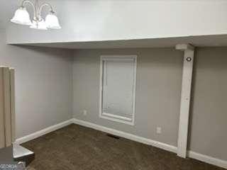 below grade area with a notable chandelier, radiator heating unit, and baseboards