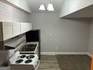 kitchen featuring a chandelier, electric stove, baseboards, and vaulted ceiling