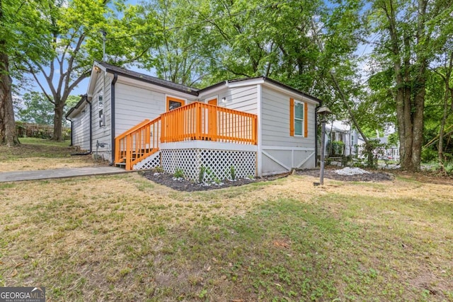 view of front of home with a deck and a front lawn