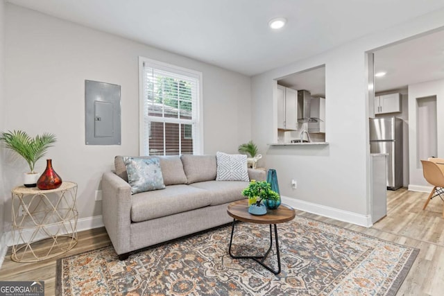 living room with electric panel, baseboards, light wood-style flooring, and recessed lighting