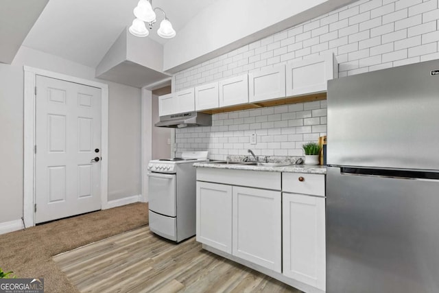 kitchen featuring backsplash, under cabinet range hood, freestanding refrigerator, white range with electric stovetop, and a sink