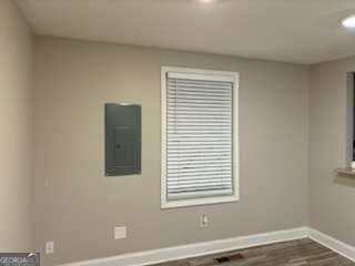 empty room featuring electric panel, baseboards, and dark wood-style flooring