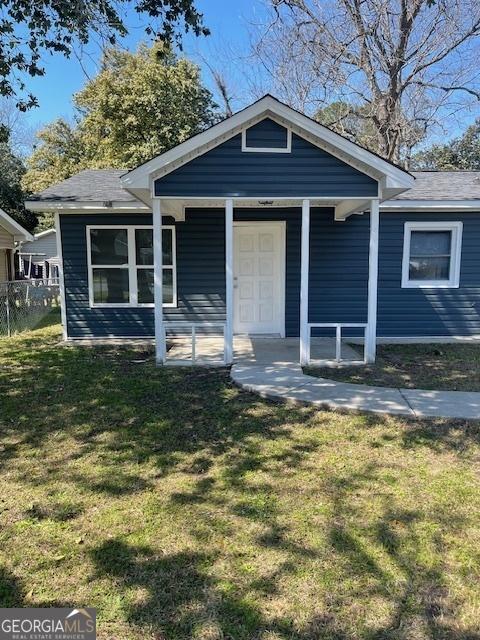 bungalow-style house with covered porch, a front lawn, and fence