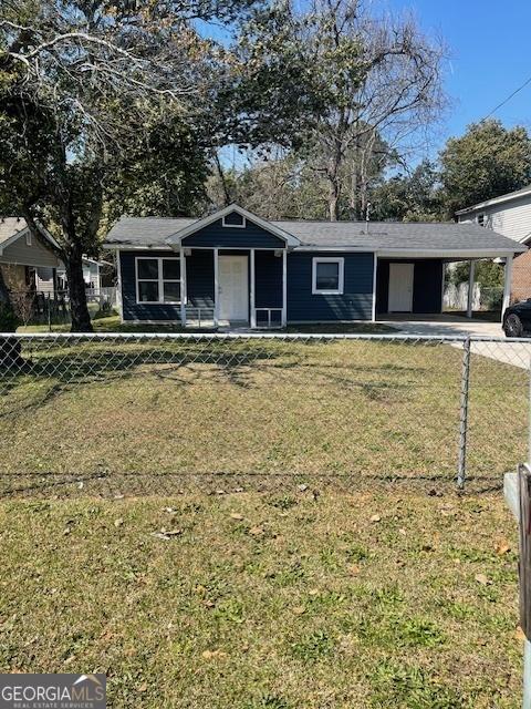 view of front of property with a fenced front yard, an attached carport, concrete driveway, and a front lawn