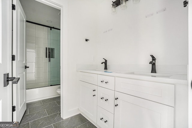 bathroom featuring a sink, toilet, double vanity, and combined bath / shower with glass door