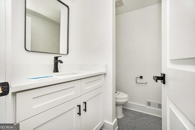 half bathroom with visible vents, toilet, vanity, and baseboards