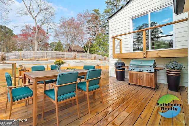 wooden deck with outdoor dining area, a grill, and a fenced backyard