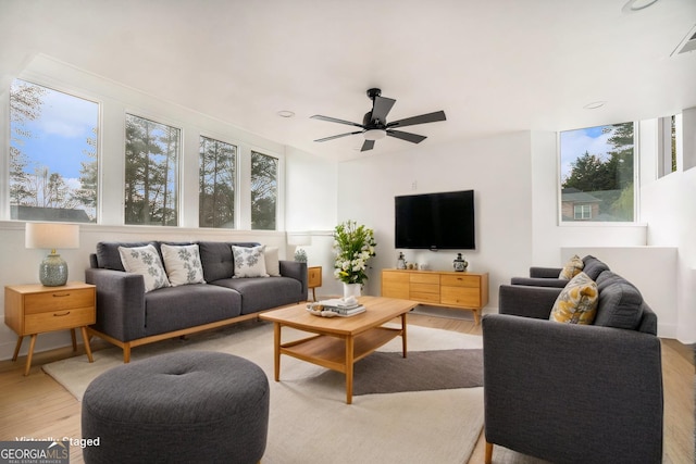 living area with light wood-style flooring, a wealth of natural light, and ceiling fan