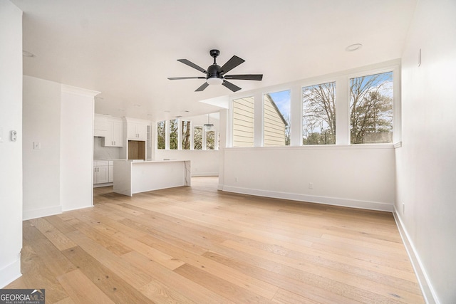 unfurnished living room featuring baseboards, light wood finished floors, and ceiling fan