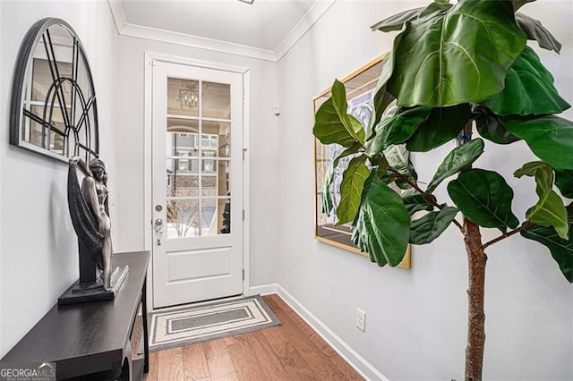 doorway featuring wood finished floors, baseboards, and ornamental molding