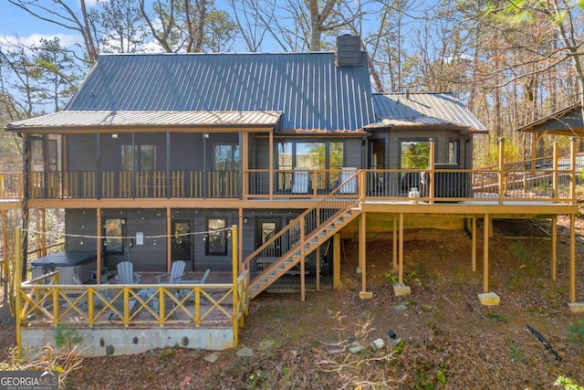 rear view of property featuring stairs, metal roof, a deck, and a chimney