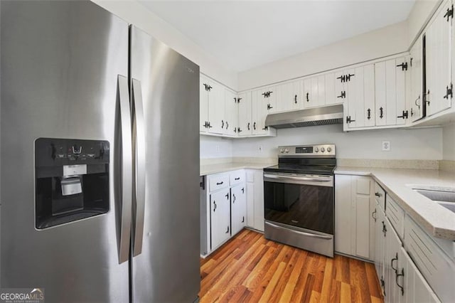 kitchen featuring under cabinet range hood, light countertops, appliances with stainless steel finishes, light wood-style floors, and white cabinets