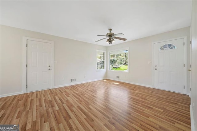 interior space featuring a ceiling fan, visible vents, light wood finished floors, and baseboards