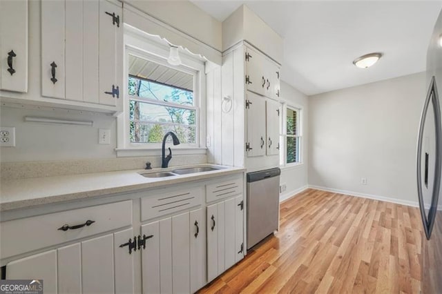 kitchen featuring light countertops, white cabinets, appliances with stainless steel finishes, and a sink