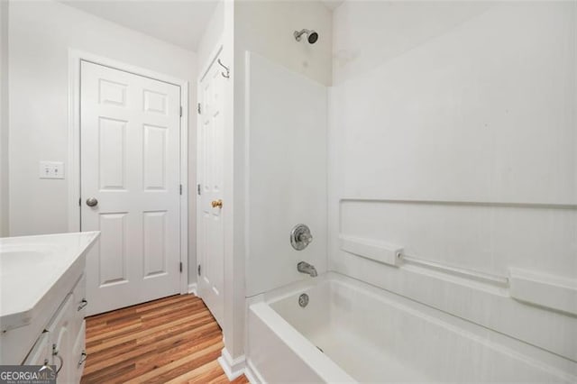 bathroom featuring vanity, washtub / shower combination, and wood finished floors