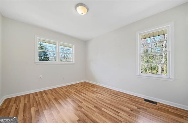 unfurnished room featuring visible vents, light wood-type flooring, and baseboards