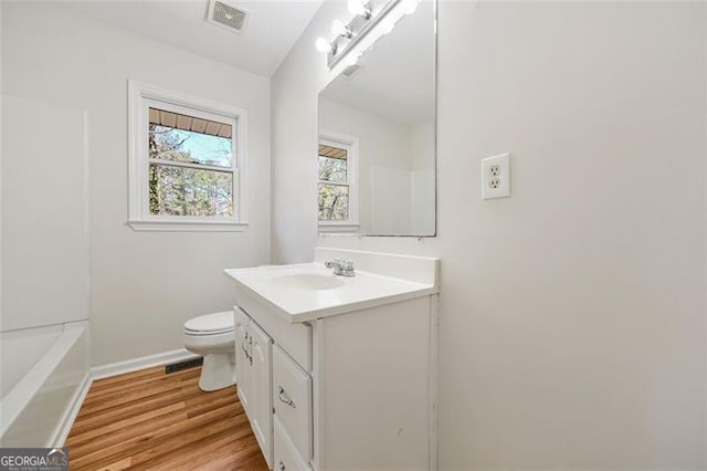 bathroom with visible vents, toilet, vanity, and wood finished floors