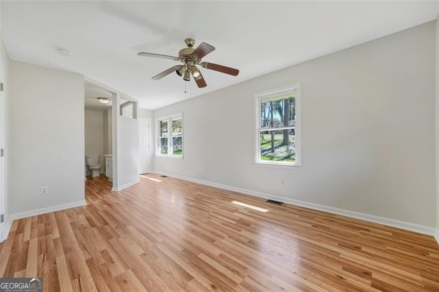 unfurnished bedroom featuring visible vents, connected bathroom, baseboards, light wood-style flooring, and a ceiling fan