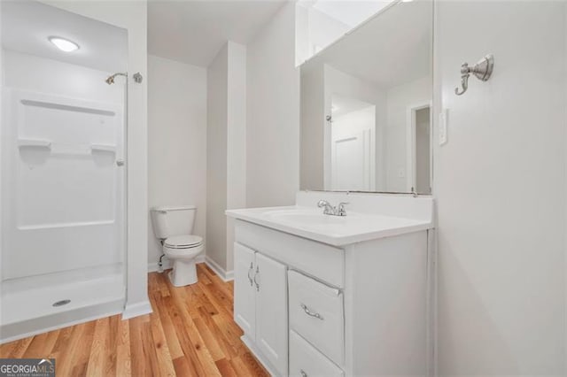 full bathroom with vanity, wood finished floors, baseboards, walk in shower, and toilet