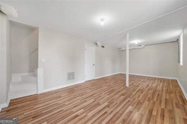 finished below grade area with visible vents, light wood-style flooring, stairway, and baseboards