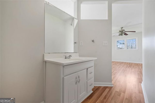 bathroom featuring baseboards, wood finished floors, ceiling fan, and vanity