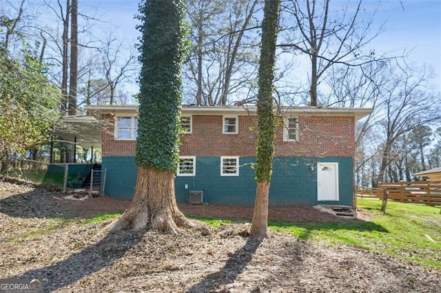 rear view of house with cooling unit, brick siding, and fence