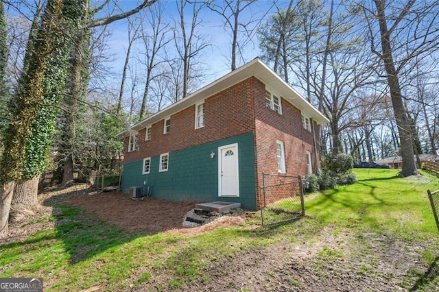 view of side of property with a yard and central AC