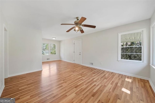 spare room featuring a ceiling fan, baseboards, and light wood-type flooring