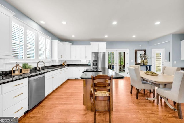 kitchen featuring light wood-style flooring, a sink, a kitchen breakfast bar, a kitchen island, and appliances with stainless steel finishes