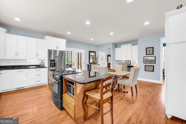 kitchen with black range with gas cooktop, white cabinetry, a breakfast bar, and stainless steel fridge with ice dispenser