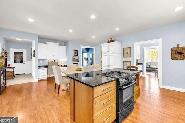 kitchen featuring light wood finished floors, black gas range, and white cabinets