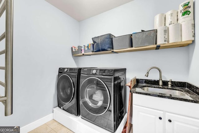 washroom with baseboards, light tile patterned flooring, cabinet space, separate washer and dryer, and a sink