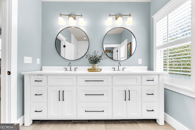 bathroom featuring double vanity, baseboards, tile patterned floors, and a sink