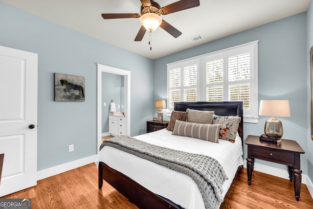 bedroom featuring connected bathroom, wood finished floors, visible vents, and baseboards