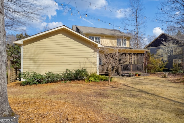 rear view of house featuring fence and a sunroom