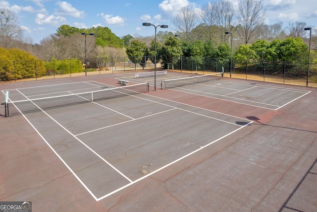 view of tennis court with community basketball court and fence