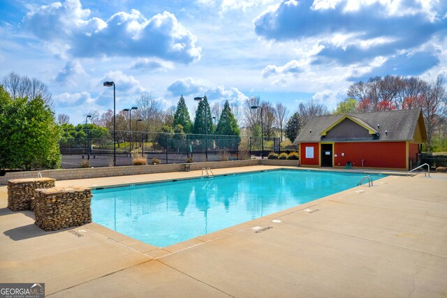 pool with a patio and fence