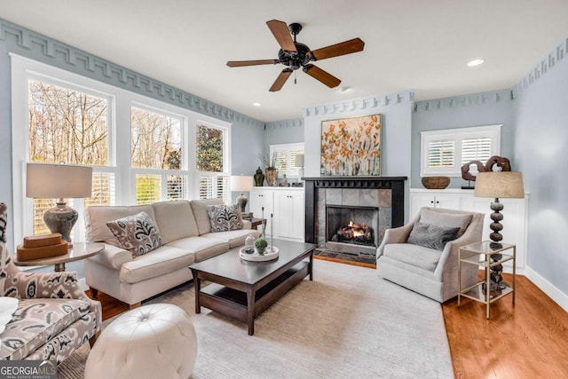 living area with baseboards, recessed lighting, a tile fireplace, wood finished floors, and a ceiling fan