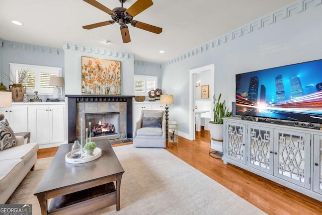 living room with recessed lighting, wood finished floors, a ceiling fan, and a tile fireplace