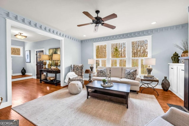 living room with a wealth of natural light, wood finished floors, and a ceiling fan