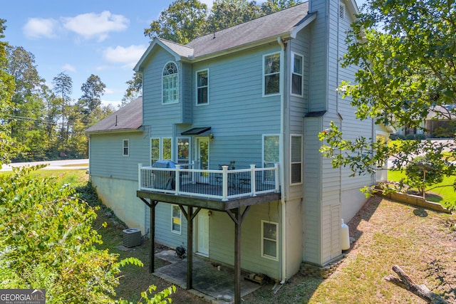 back of house featuring a wooden deck, central air condition unit, a chimney, and a shingled roof