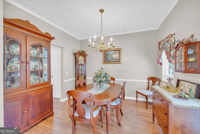 dining room featuring a textured ceiling, an inviting chandelier, light wood finished floors, and ornamental molding